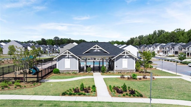 view of front of home featuring board and batten siding, a residential view, fence, and a front lawn