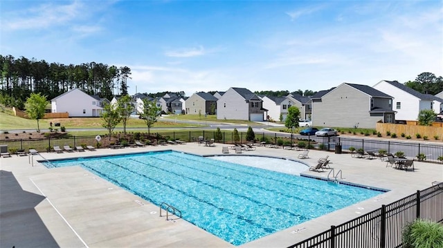 pool with a patio, fence, and a residential view