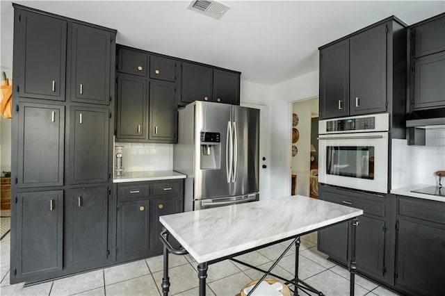 kitchen with backsplash, light tile patterned floors, and stainless steel appliances