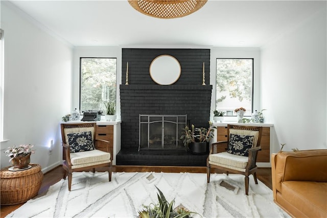 living area featuring ornamental molding, hardwood / wood-style floors, a wealth of natural light, and a fireplace