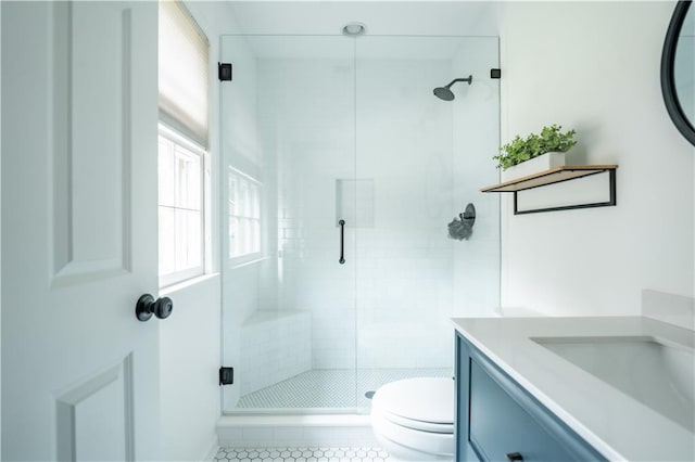 bathroom featuring toilet, vanity, tile patterned flooring, and a shower with door