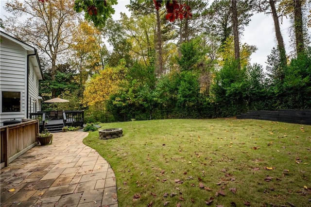 view of yard featuring a wooden deck, an outdoor fire pit, and a patio