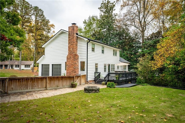 rear view of house with a deck, a yard, and an outdoor fire pit