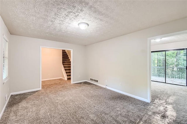 carpeted empty room with a textured ceiling