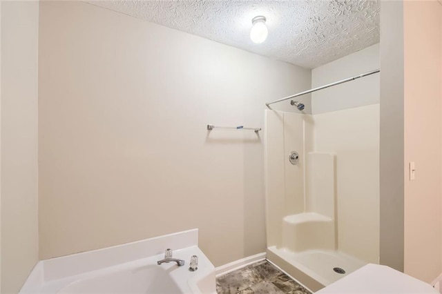 bathroom with a textured ceiling, toilet, and separate shower and tub