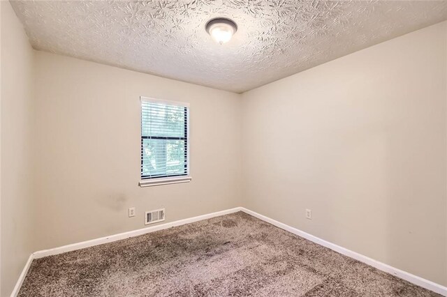 carpeted spare room featuring a textured ceiling