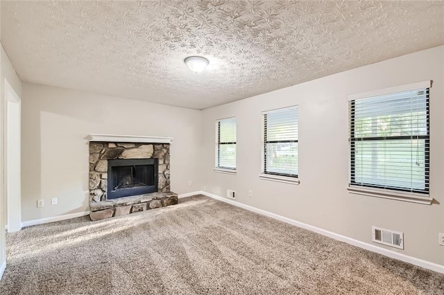 unfurnished living room featuring a textured ceiling, carpet flooring, and a fireplace