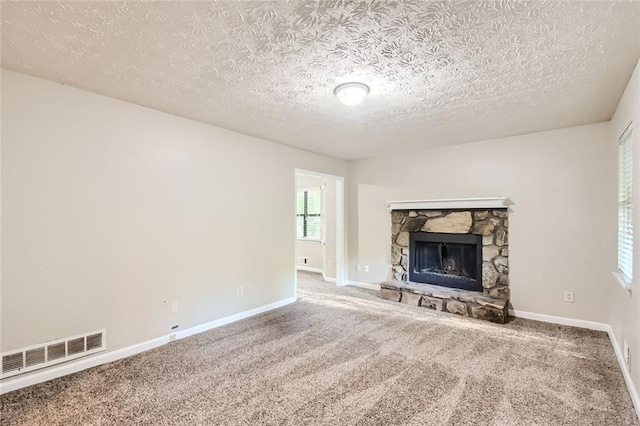 unfurnished living room with a textured ceiling, carpet floors, and a fireplace