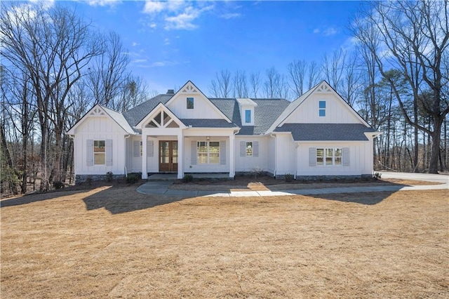 modern farmhouse style home with a shingled roof, a front yard, board and batten siding, and french doors