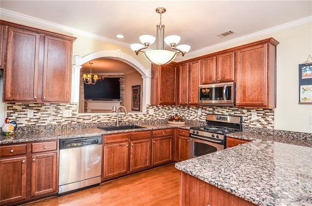 kitchen with an inviting chandelier, stainless steel appliances, sink, and pendant lighting