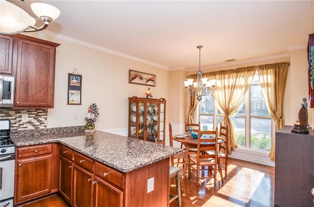 kitchen with a chandelier, kitchen peninsula, gas range gas stove, and backsplash