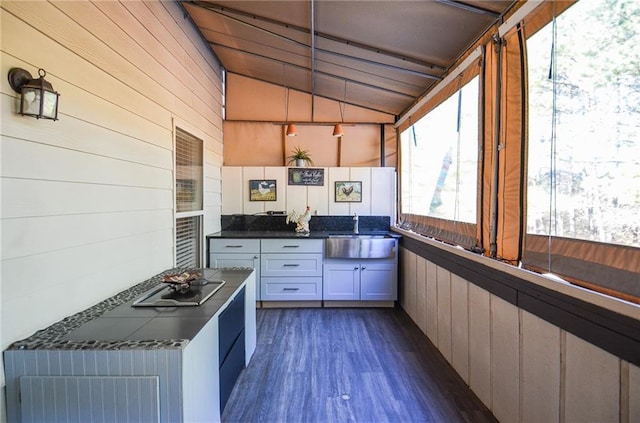 kitchen with wood walls, lofted ceiling, sink, and white cabinets