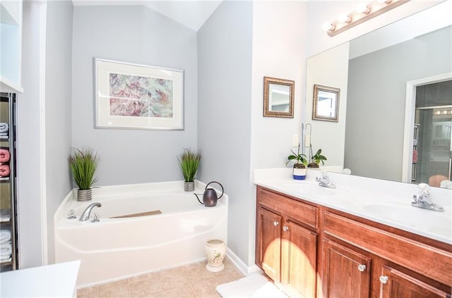 bathroom with vanity, tile patterned flooring, vaulted ceiling, and a washtub