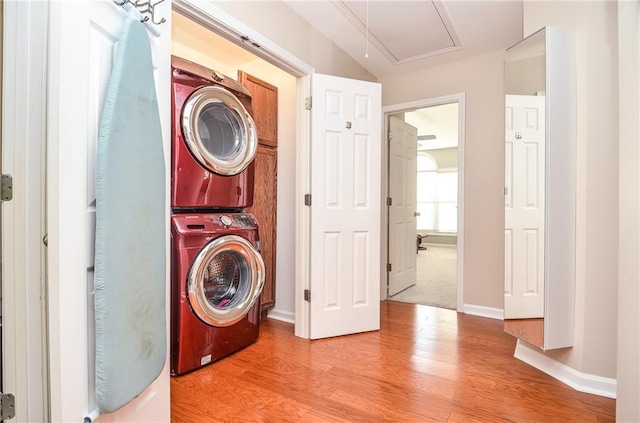 washroom featuring stacked washer / dryer and light hardwood / wood-style flooring