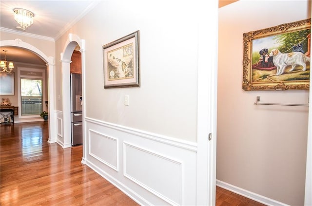 hallway featuring crown molding, a notable chandelier, hardwood / wood-style floors, and ornate columns