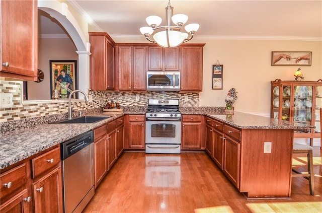 kitchen featuring appliances with stainless steel finishes, sink, a kitchen bar, kitchen peninsula, and an inviting chandelier