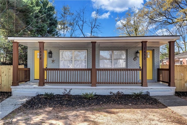 view of front of property featuring fence, a porch, and brick siding