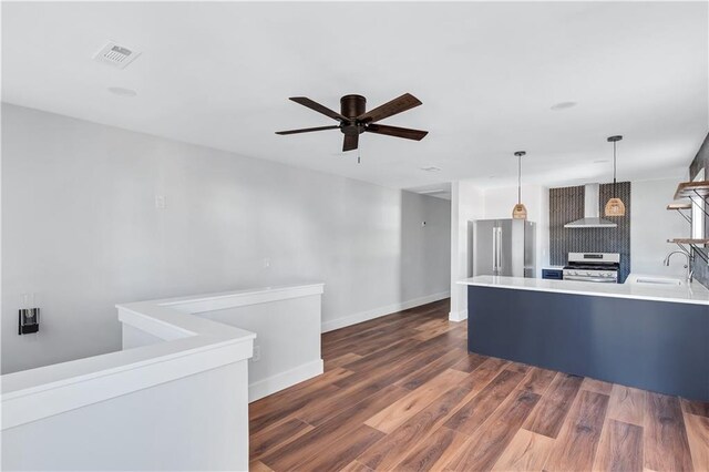 kitchen with a sink, wall chimney exhaust hood, high end refrigerator, visible vents, and range with gas cooktop
