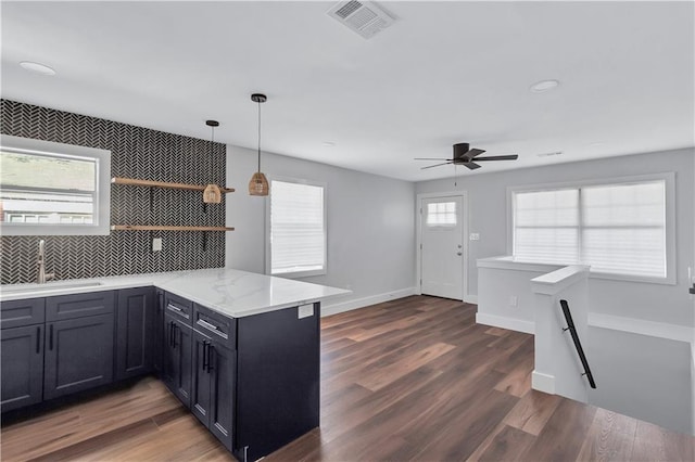 kitchen with visible vents, a peninsula, ceiling fan, wood finished floors, and a sink