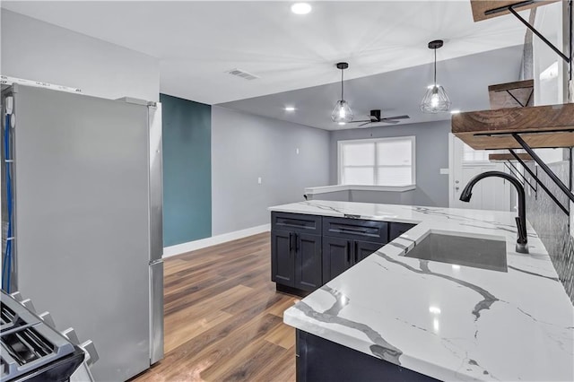 kitchen featuring visible vents, a ceiling fan, a sink, hanging light fixtures, and freestanding refrigerator