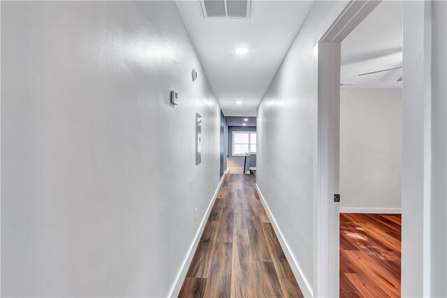 hall featuring baseboards, visible vents, and dark wood finished floors