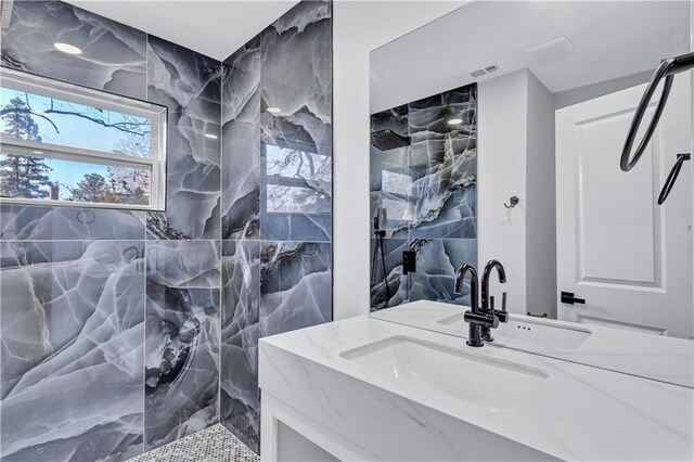 full bath with vanity, tiled shower, and visible vents