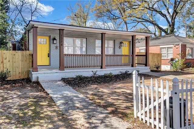view of front of house with brick siding, fence, and a porch