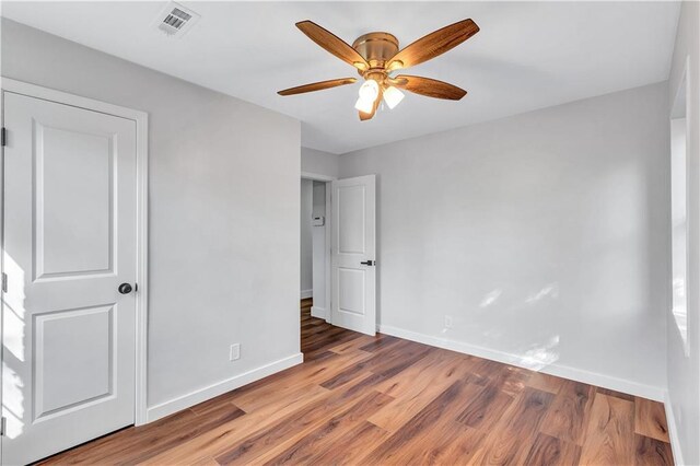 unfurnished bedroom with a ceiling fan, visible vents, baseboards, and wood finished floors