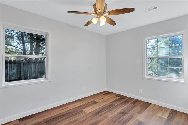 unfurnished room with baseboards, ceiling fan, visible vents, and wood finished floors