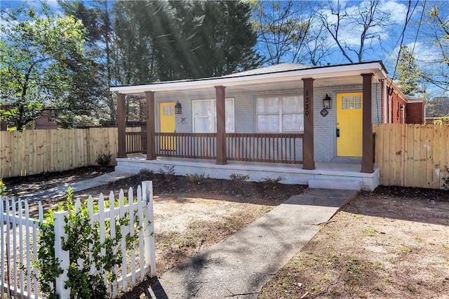 view of front of property featuring covered porch, brick siding, and fence