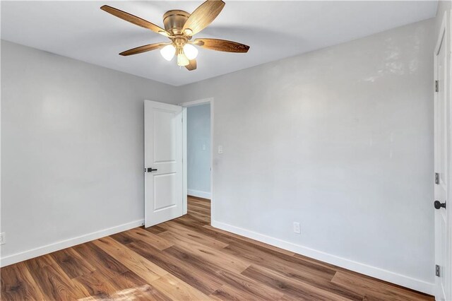 unfurnished room featuring baseboards, wood finished floors, and a ceiling fan