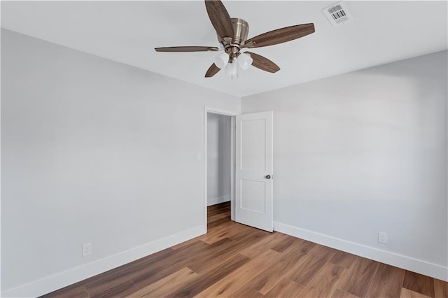 empty room featuring baseboards, visible vents, a ceiling fan, and wood finished floors