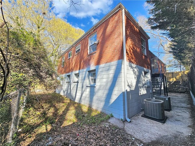 view of side of home with fence, stairway, and central AC unit