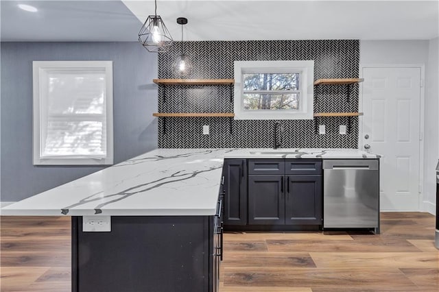 bar featuring a sink, light wood finished floors, tasteful backsplash, stainless steel dishwasher, and decorative light fixtures