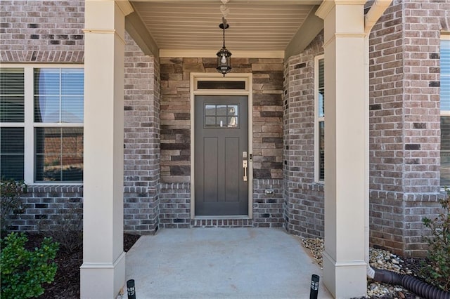 view of exterior entry with covered porch and brick siding