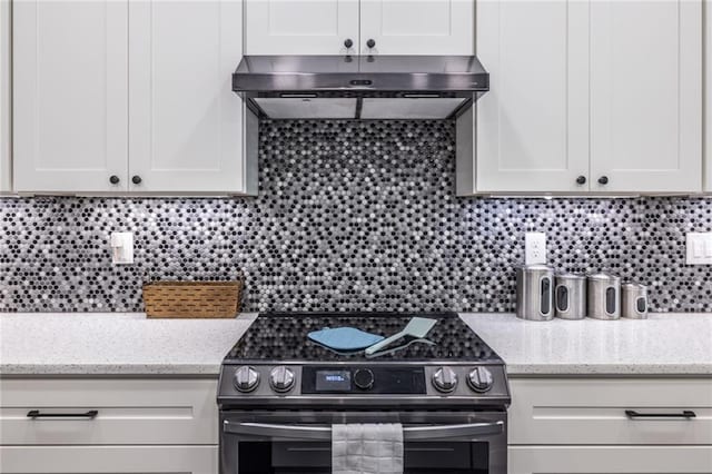 3845 Glen Ian Dr, Loganville, GA 30052 - kitchen featuring electric range, under cabinet range hood, white cabinetry, and decorative backsplash