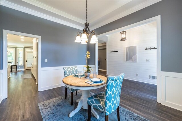 3845 Glen Ian Dr, Loganville, GA 30052 - dining room with crown molding, dark wood-style flooring, a decorative wall, a chandelier, and a wainscoted wall