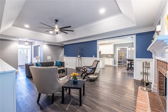 3845 Glen Ian Dr, Loganville, GA 30052 - living room with a tray ceiling, a fireplace, ceiling fan, dark wood-style flooring, and crown molding
