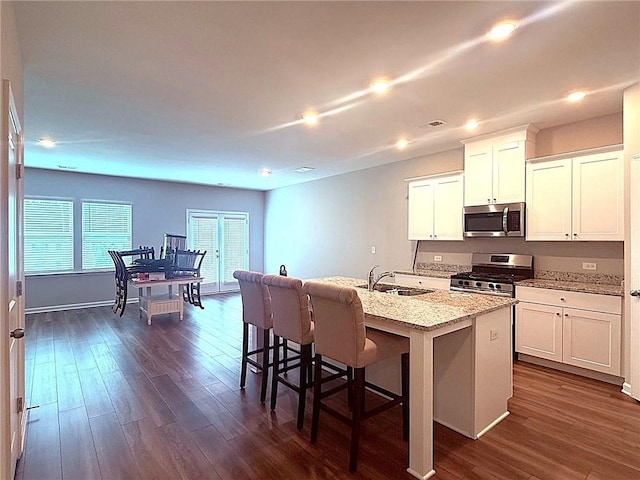 2059 Lanier Harbor Pt, Buford, GA 30518 - kitchen with stainless steel appliances, dark wood finished floors, white cabinets, a kitchen island with sink, and recessed lighting