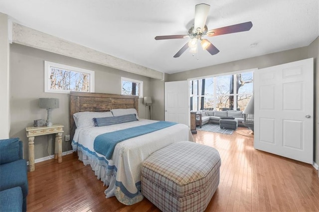 bedroom featuring hardwood / wood-style flooring, ceiling fan, and multiple windows