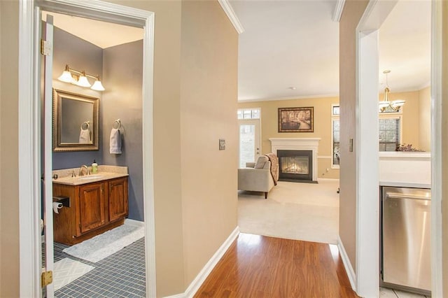 corridor featuring crown molding, a chandelier, and light hardwood / wood-style floors