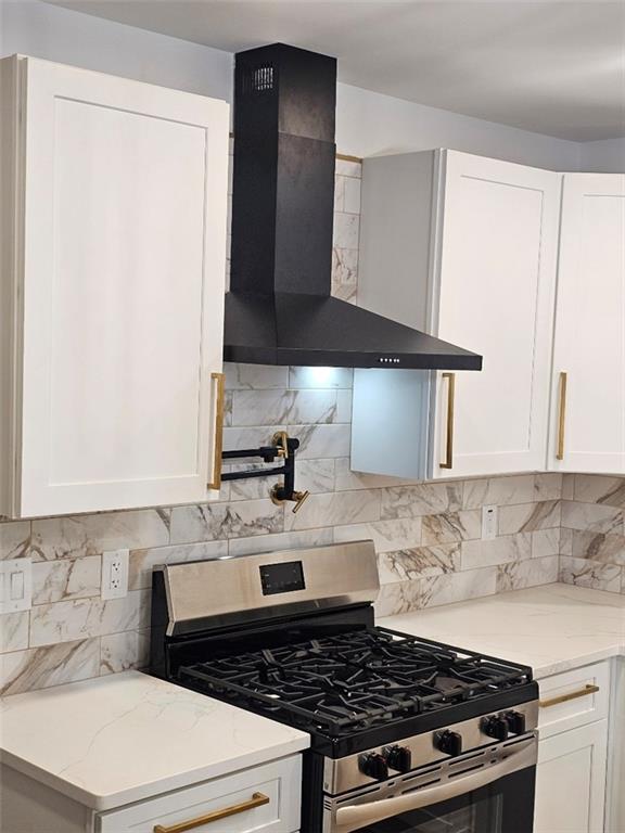 2358 Tilson Rd, Decatur, GA 30032 - kitchen with stainless steel range with gas cooktop, wall chimney range hood, white cabinetry, and decorative backsplash