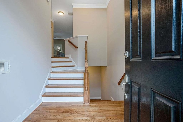 stairs featuring ornamental molding and hardwood / wood-style floors