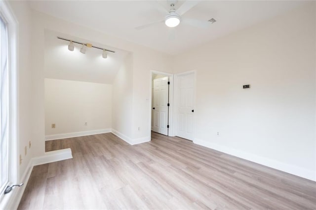 empty room with track lighting, ceiling fan, and light hardwood / wood-style flooring