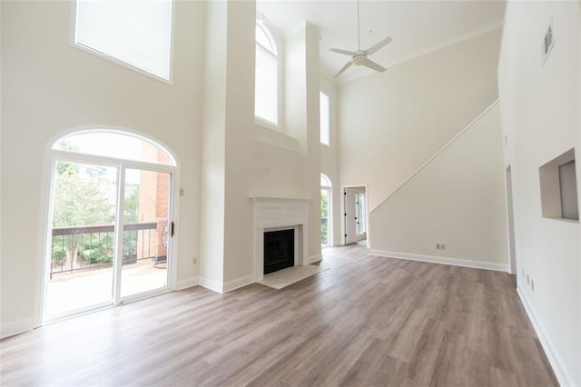 unfurnished living room featuring a high ceiling, light wood-type flooring, and plenty of natural light