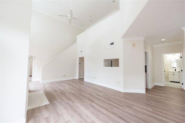 unfurnished living room featuring ceiling fan, light hardwood / wood-style flooring, a towering ceiling, and ornamental molding