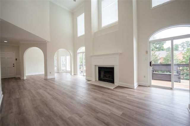 unfurnished living room featuring plenty of natural light, light wood-type flooring, and a towering ceiling