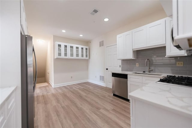 kitchen with white cabinets, light stone counters, sink, and appliances with stainless steel finishes