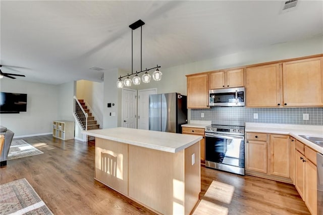 kitchen with a kitchen island, open floor plan, light countertops, appliances with stainless steel finishes, and hanging light fixtures