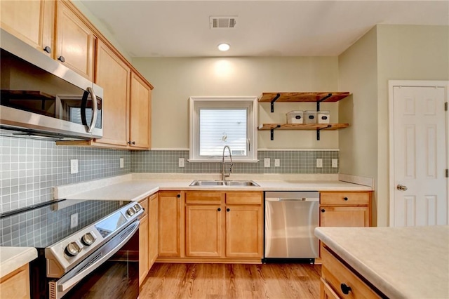 kitchen featuring stainless steel appliances, a sink, visible vents, light countertops, and backsplash